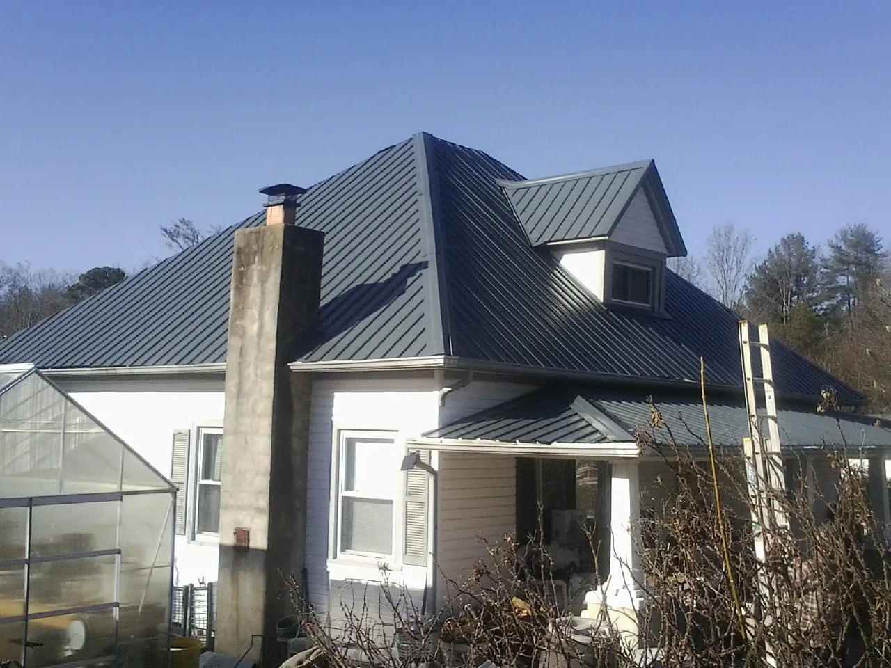 Dark blue standing seam metal roof on a white farmhouse with dormer — Slate & Tile Roof Repair by Roofing Brothers in Rensselaerville