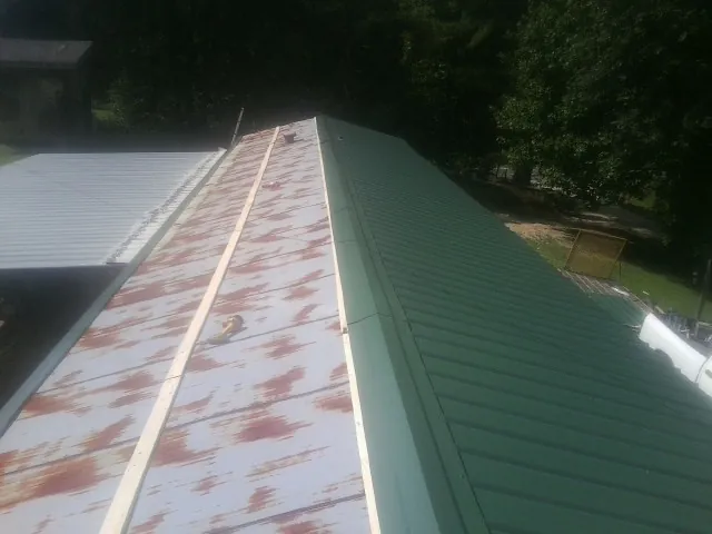 Old rusted panels beside newly installed green metal roofing — Wind Damage Roof Repair by Roofing Brothers in Rensselaerville
