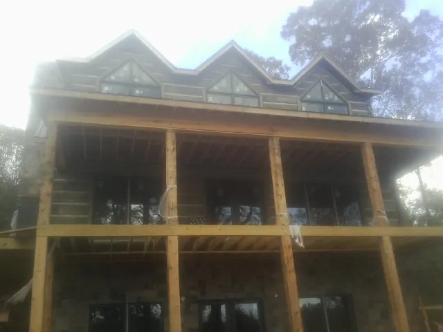 Dormers and porch framing on a large log home under construction — Roof Coating work by our crew in Rensselaerville