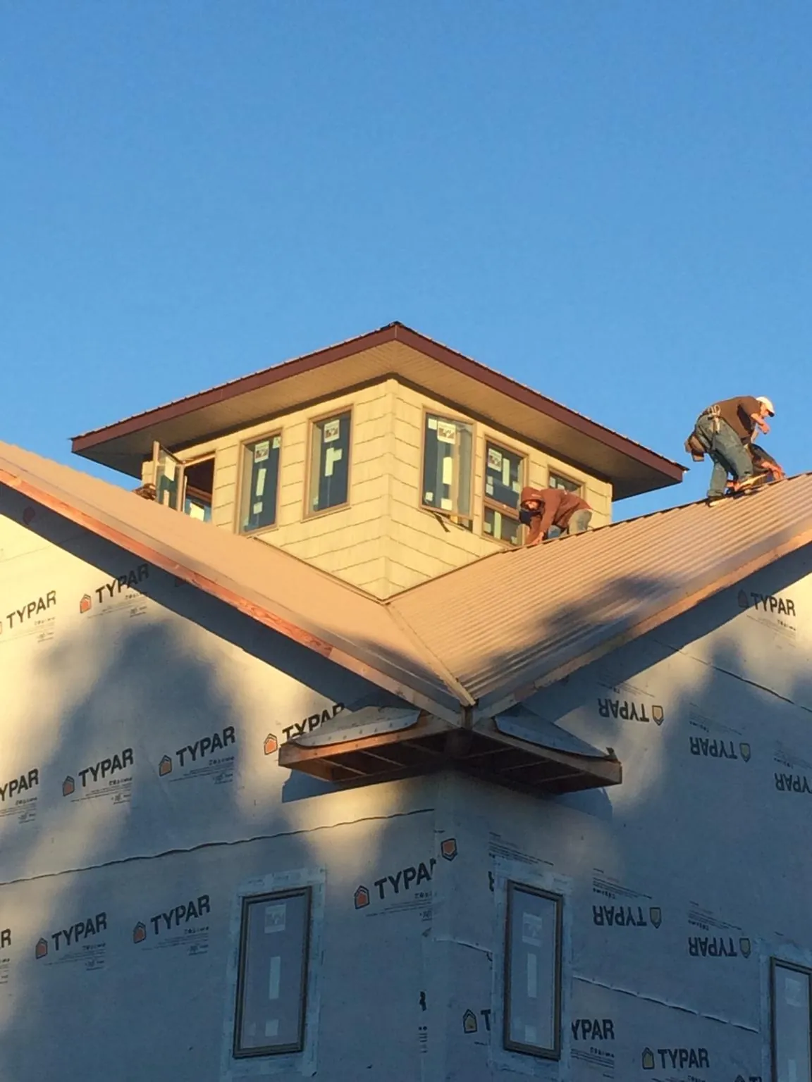 Roofers working around a rooftop cupola on a new metal roof at sunset — Roof Waterproofing in Rensselaerville by Roofing Brothers